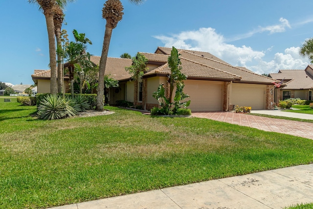8057 Cassia Dr, Boynton Beach, FL 33472 - view of front facade featuring a garage, driveway, a tile roof, a front yard, and stucco siding