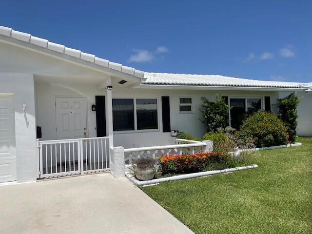 625 SW 21st Cir, Boynton Beach, FL 33426 - doorway to property featuring a yard, a tiled roof, and covered porch
