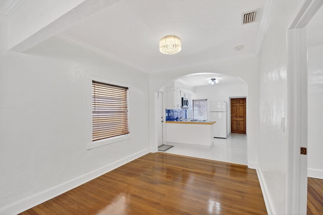 511 S K St, Lake Worth Beach, FL 33460 - unfurnished living room with arched walkways, wood finished floors, crown molding, and plenty of natural light
