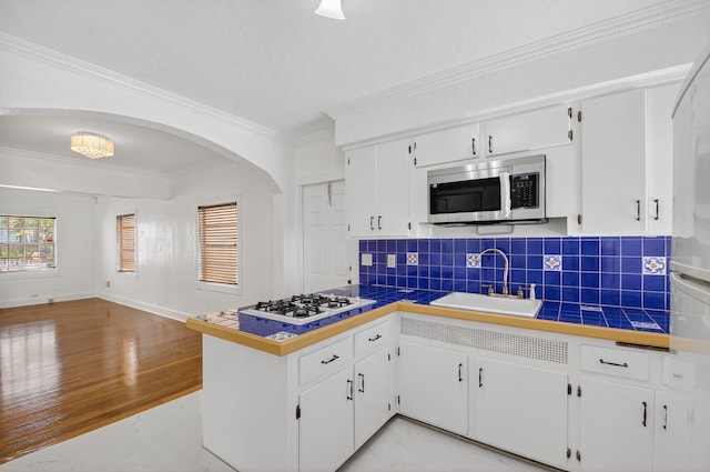 511 S K St, Lake Worth Beach, FL 33460 - kitchen with white gas stovetop, stainless steel microwave, crown molding, tasteful backsplash, and white cabinets