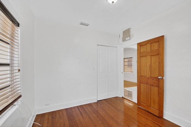 511 S K St, Lake Worth Beach, FL 33460 - unfurnished bedroom featuring multiple windows, wood finished floors, and arched walkways