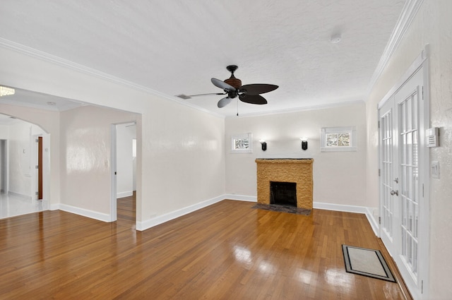 511 S K St, Lake Worth Beach, FL 33460 - unfurnished living room with wood finished floors, ceiling fan, arched walkways, a fireplace with flush hearth, and crown molding