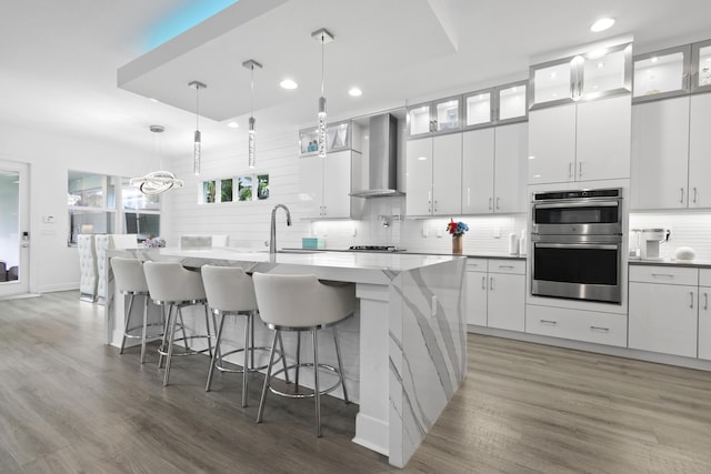 13313 Machiavelli Way, Palm Beach Gardens, FL 33418 - kitchen with wall chimney exhaust hood, double oven, recessed lighting, a kitchen island with sink, and decorative backsplash