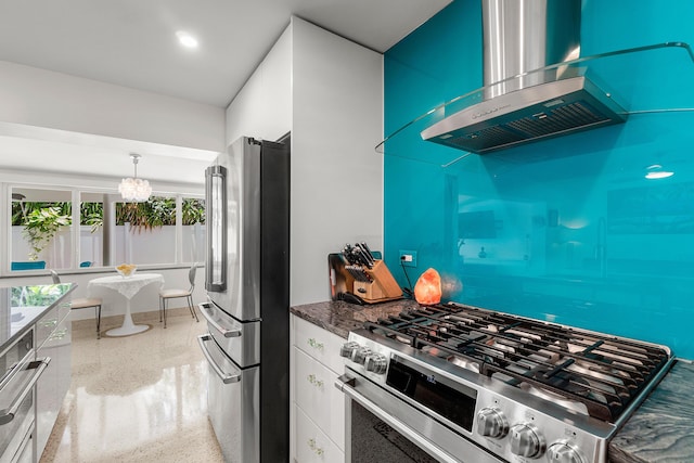 301 Linda Ln, West Palm Beach, FL 33405 - kitchen featuring appliances with stainless steel finishes, wall chimney range hood, white cabinets, dark aggregate flooring, and dark stone counters