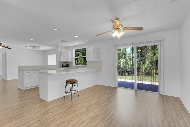 5801 SE Cable Dr, Stuart, FL 34997 - kitchen with ceiling fan, a peninsula, white cabinets, light wood-type flooring, and light countertops