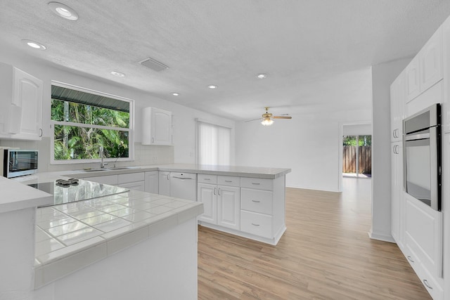 5801 SE Cable Dr, Stuart, FL 34997 - kitchen with a peninsula, oven, white dishwasher, light wood-style flooring, and recessed lighting