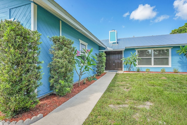 5801 SE Cable Dr, Stuart, FL 34997 - entrance to property featuring a yard, a chimney, and a metal roof