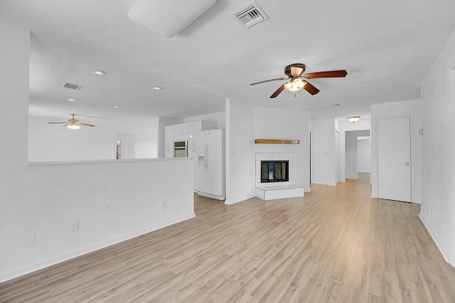 5801 SE Cable Dr, Stuart, FL 34997 - unfurnished living room with ceiling fan, light wood finished floors, a textured ceiling, recessed lighting, and a tiled fireplace