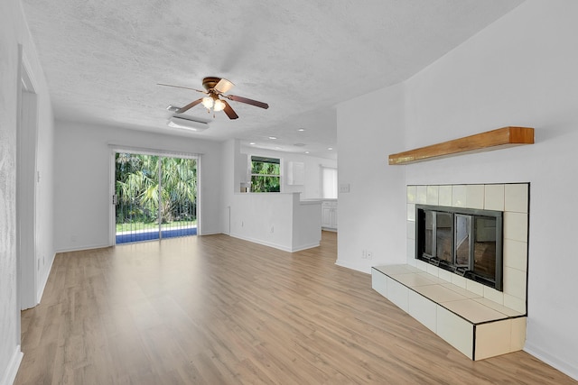 5801 SE Cable Dr, Stuart, FL 34997 - unfurnished living room with a ceiling fan, wood finished floors, a tile fireplace, and a textured ceiling