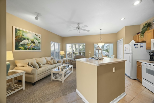9894 Perfect Dr Unit 21, Port Saint Lucie, FL 34986 - kitchen featuring white appliances, light tile patterned flooring, a ceiling fan, hanging light fixtures, and light countertops