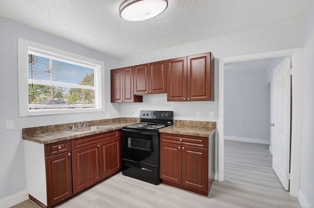 323 S E St, Lake Worth Beach, FL 33460 - kitchen with black electric range, light wood-style flooring, and a textured ceiling