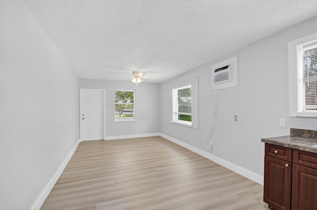 323 S E St, Lake Worth Beach, FL 33460 - unfurnished living room with a ceiling fan, a textured ceiling, an AC wall unit, and light wood-style floors