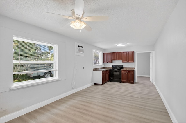 323 S E St, Lake Worth Beach, FL 33460 - kitchen featuring black electric range oven, plenty of natural light, a textured ceiling, light wood-style flooring, and an AC wall unit
