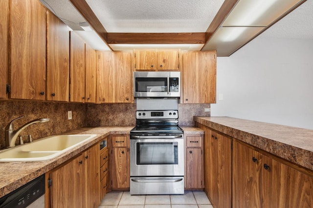 2897 SW 22nd Cir Unit 44B, Delray Beach, FL 33445 - kitchen featuring appliances with stainless steel finishes, backsplash, light tile patterned floors, brown cabinets, and a textured ceiling