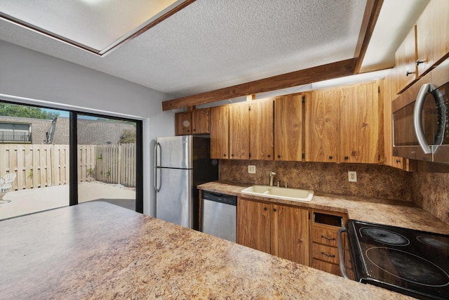 2897 SW 22nd Cir Unit 44B, Delray Beach, FL 33445 - kitchen with appliances with stainless steel finishes, backsplash, brown cabinetry, light countertops, and a textured ceiling