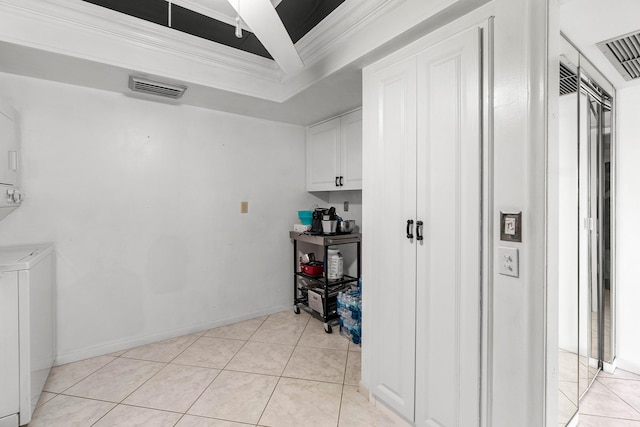 2400 Presidential Way Unit 903, West Palm Beach, FL 33401 - kitchen with ornamental molding, white cabinets, light tile patterned floors, and stacked washing machine and dryer