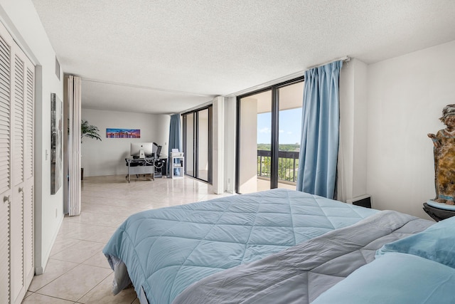 2400 Presidential Way Unit 903, West Palm Beach, FL 33401 - bedroom featuring access to exterior, a desk, light tile patterned flooring, a wall of windows, and a textured ceiling