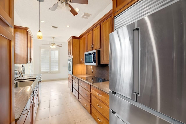 2619 SW Greenwich Way, Palm City, FL 34990 - kitchen with appliances with stainless steel finishes, ceiling fan, brown cabinetry, light tile patterned flooring, and decorative light fixtures