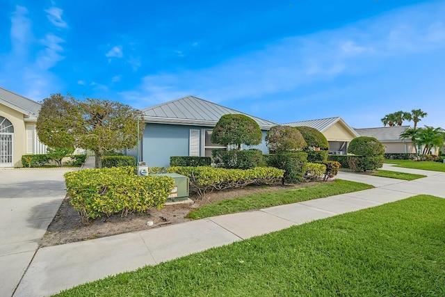 2619 SW Greenwich Way, Palm City, FL 34990 - view of front facade with a standing seam roof, driveway, a front lawn, a metal roof, and stucco siding
