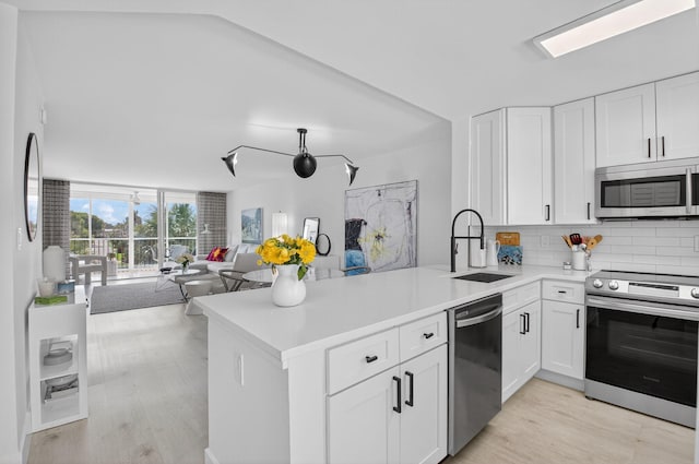 930 Dogwood Dr Unit 358, Delray Beach, FL 33483 - kitchen featuring stainless steel appliances, backsplash, open floor plan, light wood-type flooring, and a peninsula