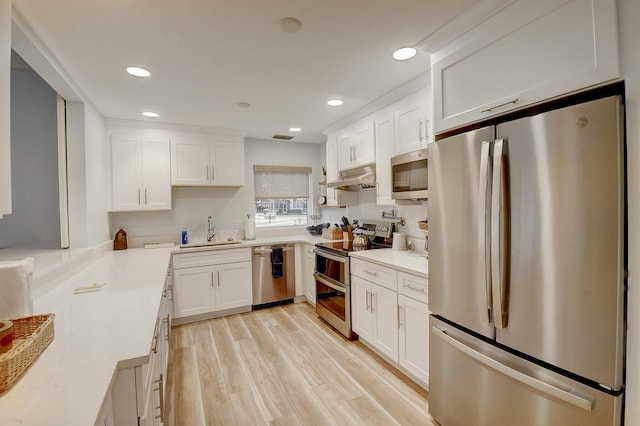 930 Dogwood Dr Unit 358, Delray Beach, FL 33483 - kitchen with appliances with stainless steel finishes, under cabinet range hood, white cabinets, light wood finished floors, and light countertops