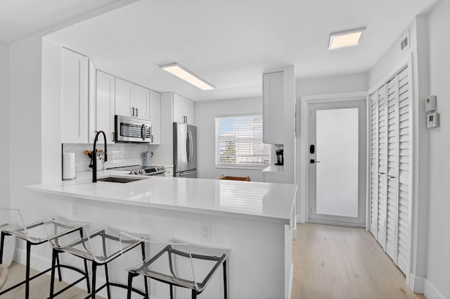 930 Dogwood Dr Unit 358, Delray Beach, FL 33483 - kitchen with appliances with stainless steel finishes, decorative backsplash, light wood-type flooring, light countertops, and white cabinetry