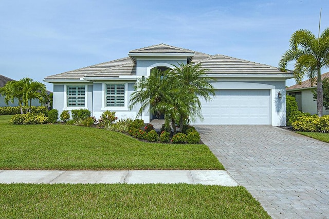 3165 Berkley Square Way, Vero Beach, FL 32966 - view of front of home with an attached garage, decorative driveway, a front yard, stucco siding, and a tiled roof