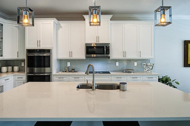 3165 Berkley Square Way, Vero Beach, FL 32966 - kitchen with appliances with stainless steel finishes, a center island with sink, white cabinetry, tasteful backsplash, and crown molding