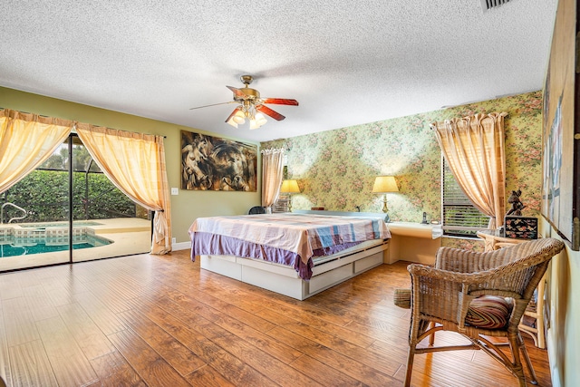 2029 Greenview Cove Dr, Wellington, FL 33414 - bedroom featuring wallpapered walls, access to outside, hardwood / wood-style floors, a textured ceiling, and ceiling fan
