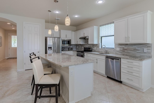 649 SE Monteiro Dr, Port Saint Lucie, FL 34984 - kitchen with stainless steel appliances, arched walkways, decorative backsplash, under cabinet range hood, and white cabinetry