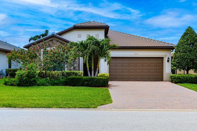 649 SE Monteiro Dr, Port Saint Lucie, FL 34984 - mediterranean / spanish-style home with a garage, a front lawn, decorative driveway, stucco siding, and a tiled roof