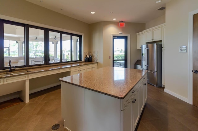 649 SE Monteiro Dr, Port Saint Lucie, FL 34984 - kitchen featuring high end refrigerator, white cabinets, light stone counters, recessed lighting, and a center island