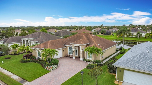 780 SW Fortunella Cir SW, Vero Beach, FL 32968 - view of front of home featuring decorative driveway, a residential view, an attached garage, stucco siding, and a water view