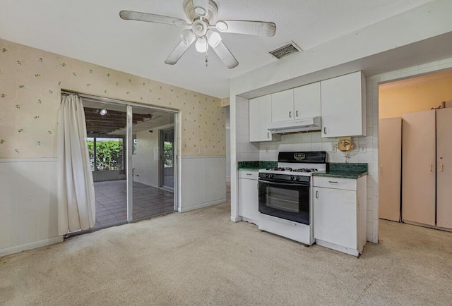 4840 Pineaire Ln, West Palm Beach, FL 33417 - kitchen with gas stove, under cabinet range hood, wallpapered walls, wainscoting, and white cabinets