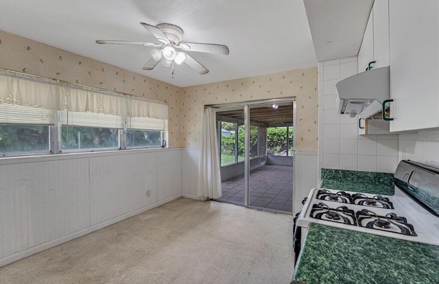 4840 Pineaire Ln, West Palm Beach, FL 33417 - kitchen featuring range with gas cooktop, exhaust hood, a wainscoted wall, ceiling fan, and white cabinets