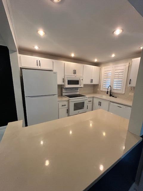 808 SE 7th St Unit 107, Deerfield Beach, FL 33441 - kitchen with white appliances, white cabinetry, light countertops, recessed lighting, and decorative backsplash
