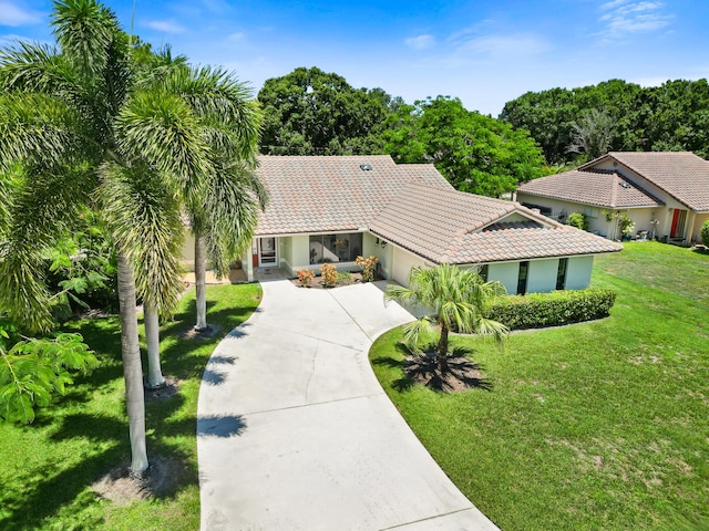 3003 SW Seaboard Ave, Palm City, FL 34990 - view of front of house featuring a tiled roof, an attached garage, driveway, a front yard, and stucco siding