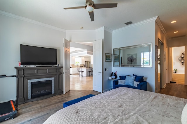 11355 SW Rockingham Dr, Port Saint Lucie, FL 34987 - bedroom featuring wood finished floors, ornamental molding, a glass covered fireplace, freestanding refrigerator, and recessed lighting