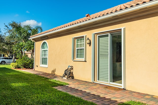 11355 SW Rockingham Dr, Port Saint Lucie, FL 34987 - view of property exterior with a yard, a tile roof, a patio area, and stucco siding