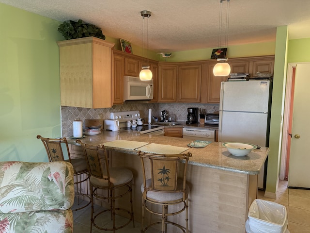 2400 S Ocean Dr S Unit 1011, Fort Pierce, FL 34949 - kitchen featuring white appliances, a peninsula, tasteful backsplash, a breakfast bar, and a textured ceiling
