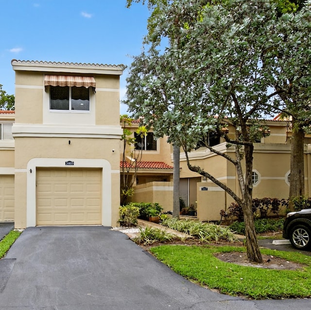 3469 Deer Creek Palladian Cir, Deerfield Beach, FL 33442 - view of property featuring a tiled roof, stucco siding, an attached garage, and asphalt driveway