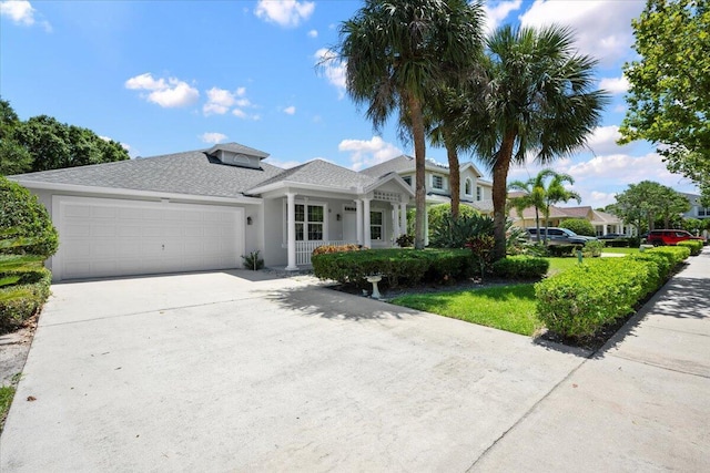 204 Clocktower Dr, Jupiter, FL 33458 - view of front of home with a garage, concrete driveway, a porch, stucco siding, and roof with shingles