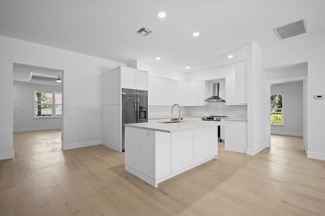204 Clocktower Dr, Jupiter, FL 33458 - kitchen with stainless steel appliances, wall chimney range hood, light wood-style floors, light countertops, and white cabinets