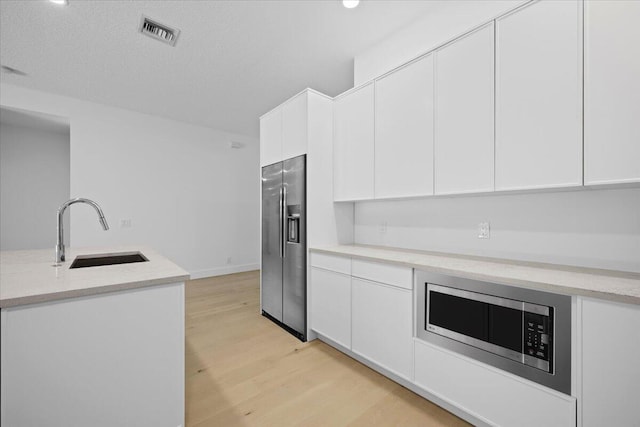 204 Clocktower Dr, Jupiter, FL 33458 - kitchen with stainless steel appliances, light wood-type flooring, white cabinets, and modern cabinets