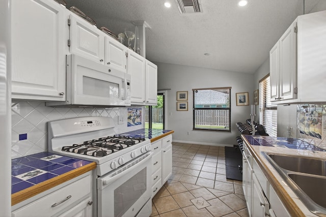6093 Lucerne St, Jupiter, FL 33458 - kitchen featuring white appliances, tile counters, tasteful backsplash, white cabinets, and vaulted ceiling