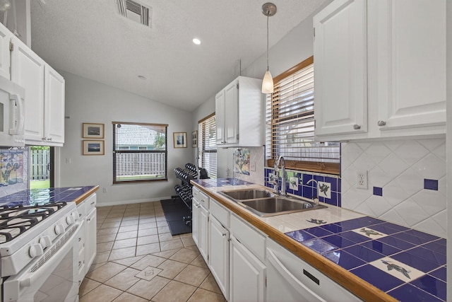 6093 Lucerne St, Jupiter, FL 33458 - kitchen with white appliances, tasteful backsplash, white cabinets, vaulted ceiling, and hanging light fixtures