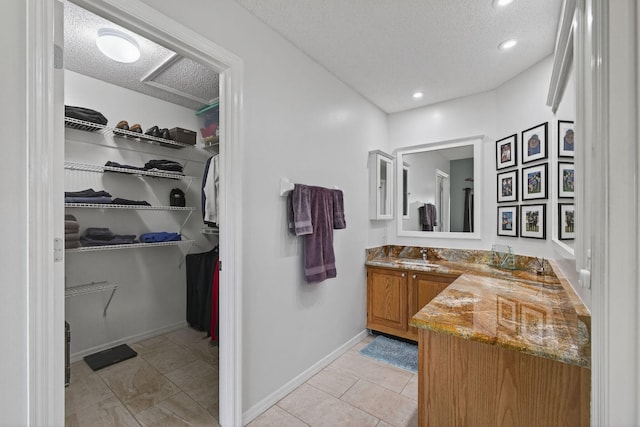 6093 Lucerne St, Jupiter, FL 33458 - bathroom featuring vanity, a walk in closet, a textured ceiling, tile patterned flooring, and recessed lighting
