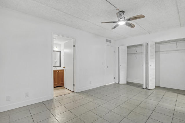 300 Village Green Cir S Unit 120, Palm Springs, FL 33461 - unfurnished bedroom with two closets, light tile patterned flooring, a textured ceiling, ensuite bathroom, and a ceiling fan