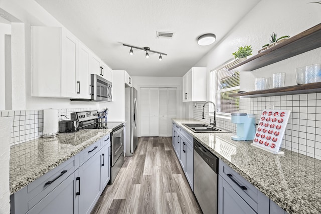 126 NW 6th Ave, Delray Beach, FL 33444 - kitchen with stainless steel appliances, open shelves, light stone counters, and backsplash
