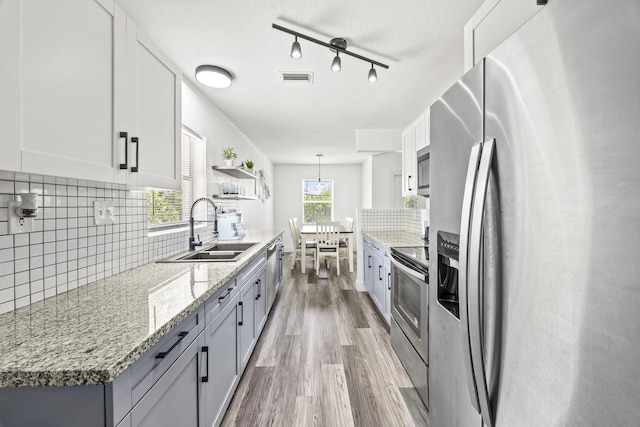 126 NW 6th Ave, Delray Beach, FL 33444 - kitchen featuring appliances with stainless steel finishes, light wood-type flooring, backsplash, light stone counters, and white cabinets